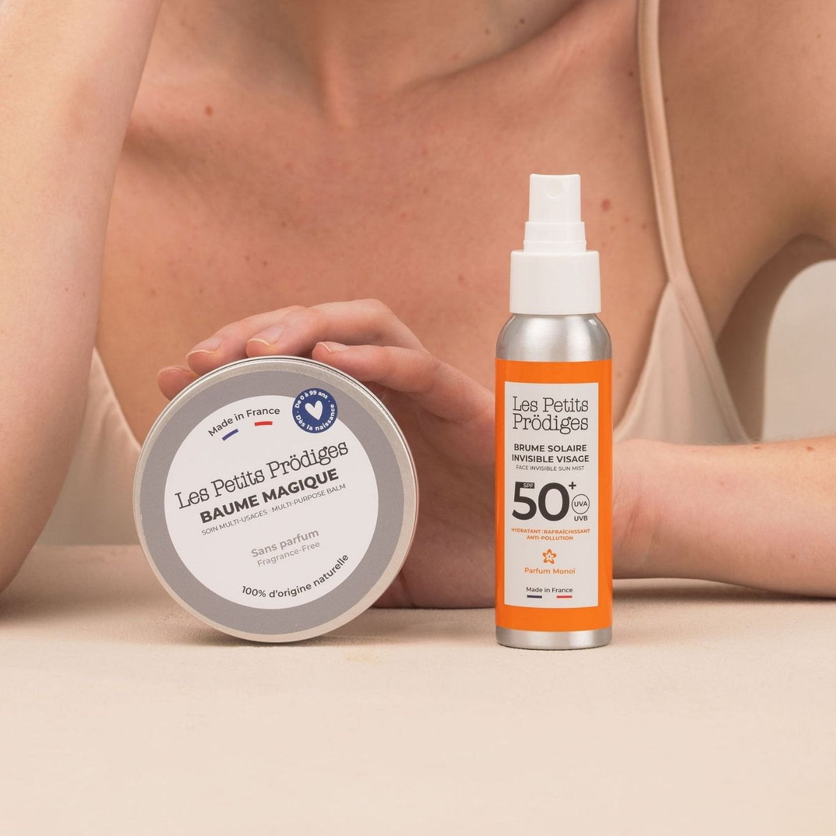 Baume Magique et Brume Solaire Invisible SPF 50+ posés devant une femme