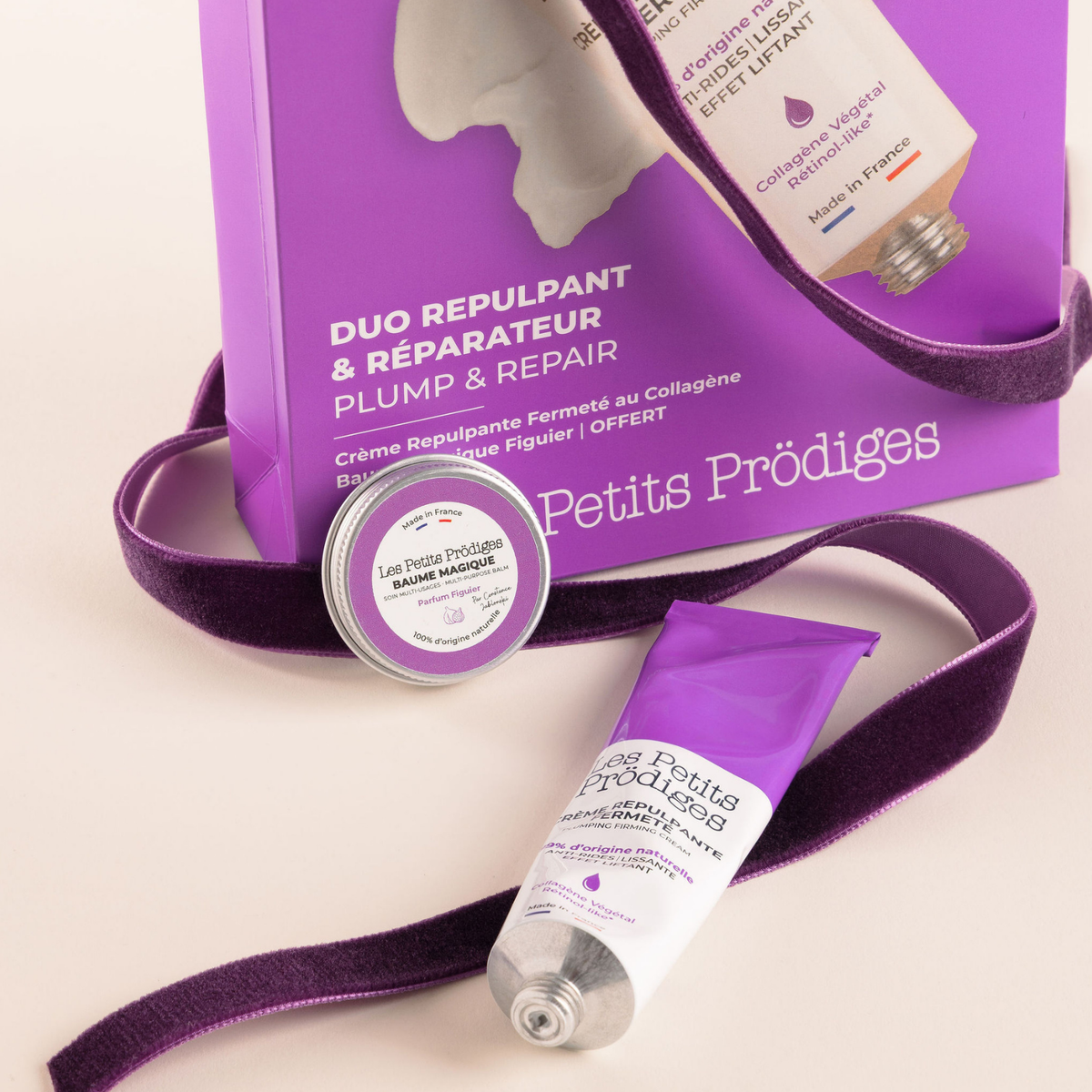 Duo Repulpant & Réparateur Les Petits Prödiges, avec la Crème Repulpante Fermeté et le Baume Magique Figuier devant leur coffret violet.