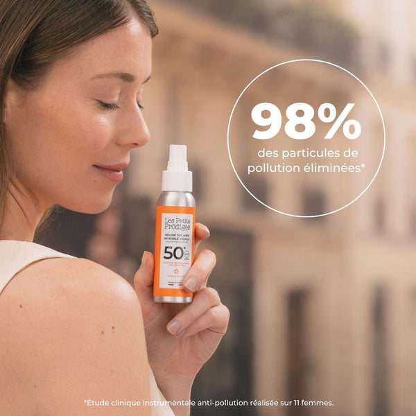 Femme tenant la Brume Solaire Invisible SPF 50+ en ville, 98 % des particules de pollution éliminées