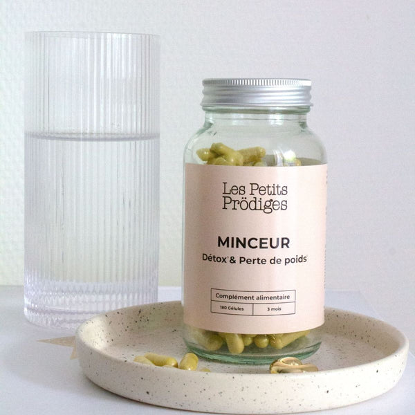 Pilulier Cure Détox Minceur Les Petits Prödiges et ses gélules, à côté d'un verre d'eau