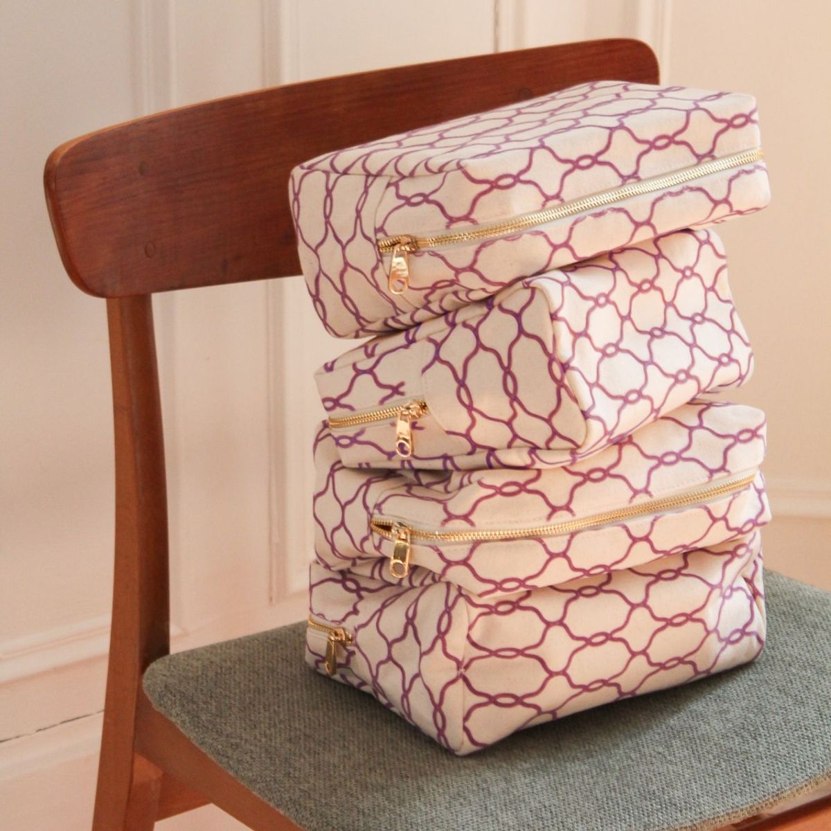 Trousses d'été Les Petits Prödiges à motif violet empilées sur une chaise