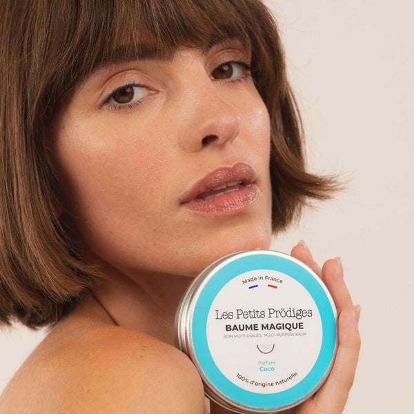 Femme aux cheveux courts tenant le Baume Magique Coco contre son épaule