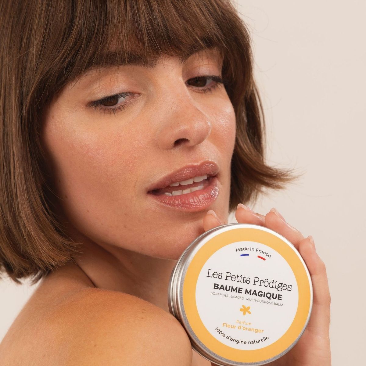 Femme aux cheveux courts tenant le Baume Magique Fleur d'Oranger contre sa joue