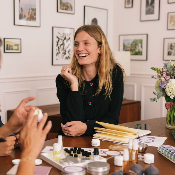 Femme souriante lors d'un atelier de création de parfum autour d'une table
