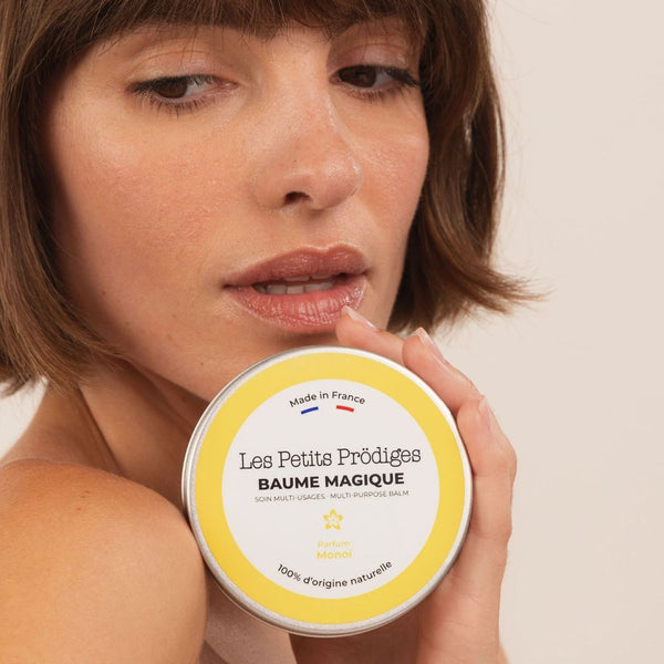 Femme aux cheveux courts tenant le Baume Magique Monoï contre sa joue
