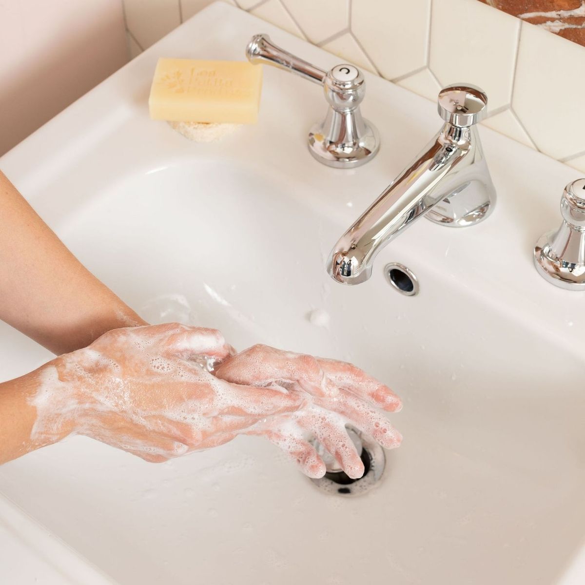 Mains se lavant avec le Savon Peau Douce au-dessus d'un lavabo