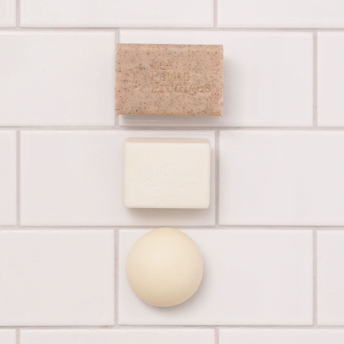 Savon, Shampoing Solide Amande et boule de soin fixés sur un carrelage blanc
