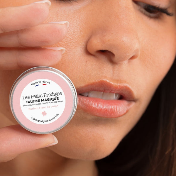 Femme tenant un mini pot de Baume Magique Fleur de Coton contre sa joue